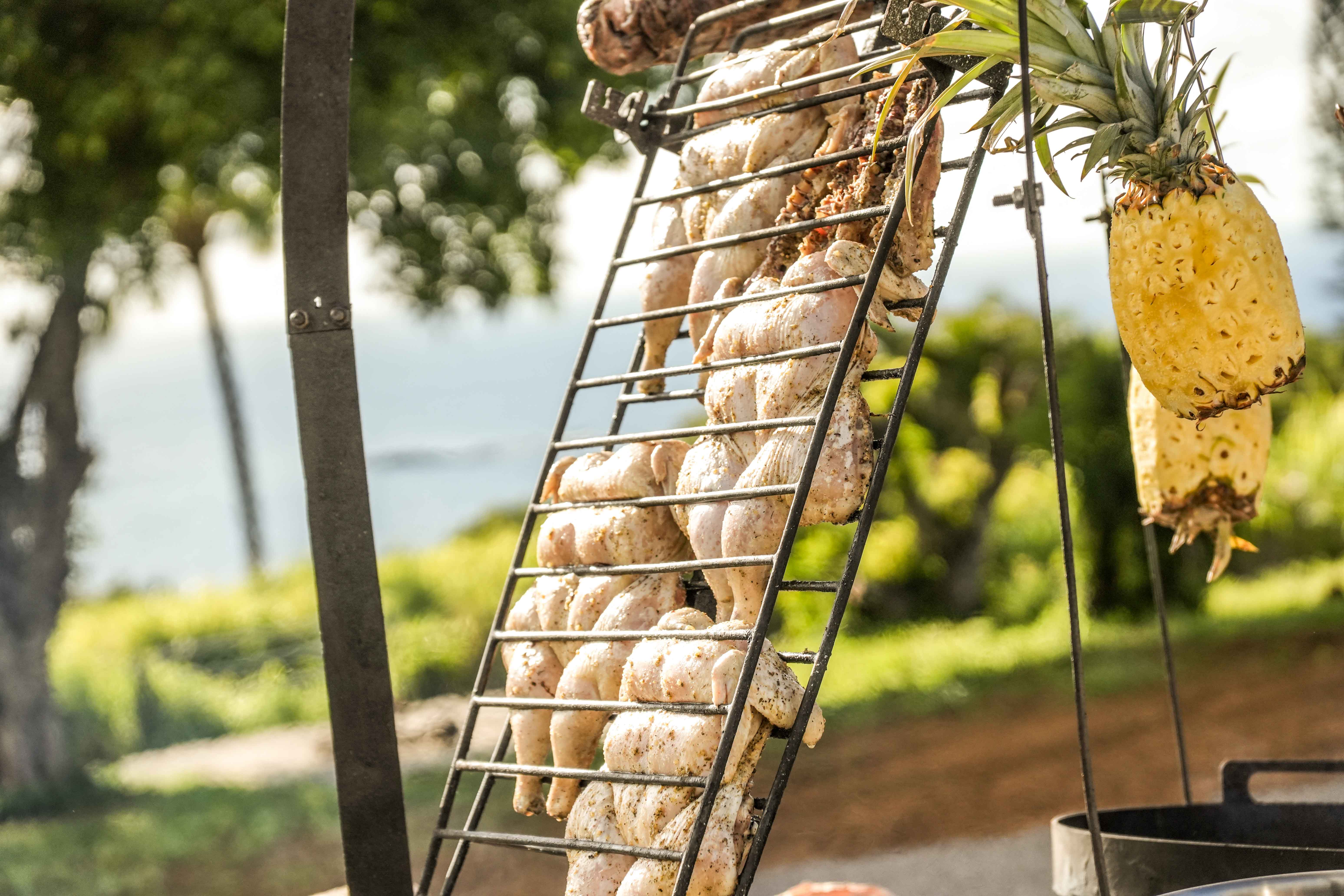 Meat and pineapple roasting on the asado rack with the ocean beyond