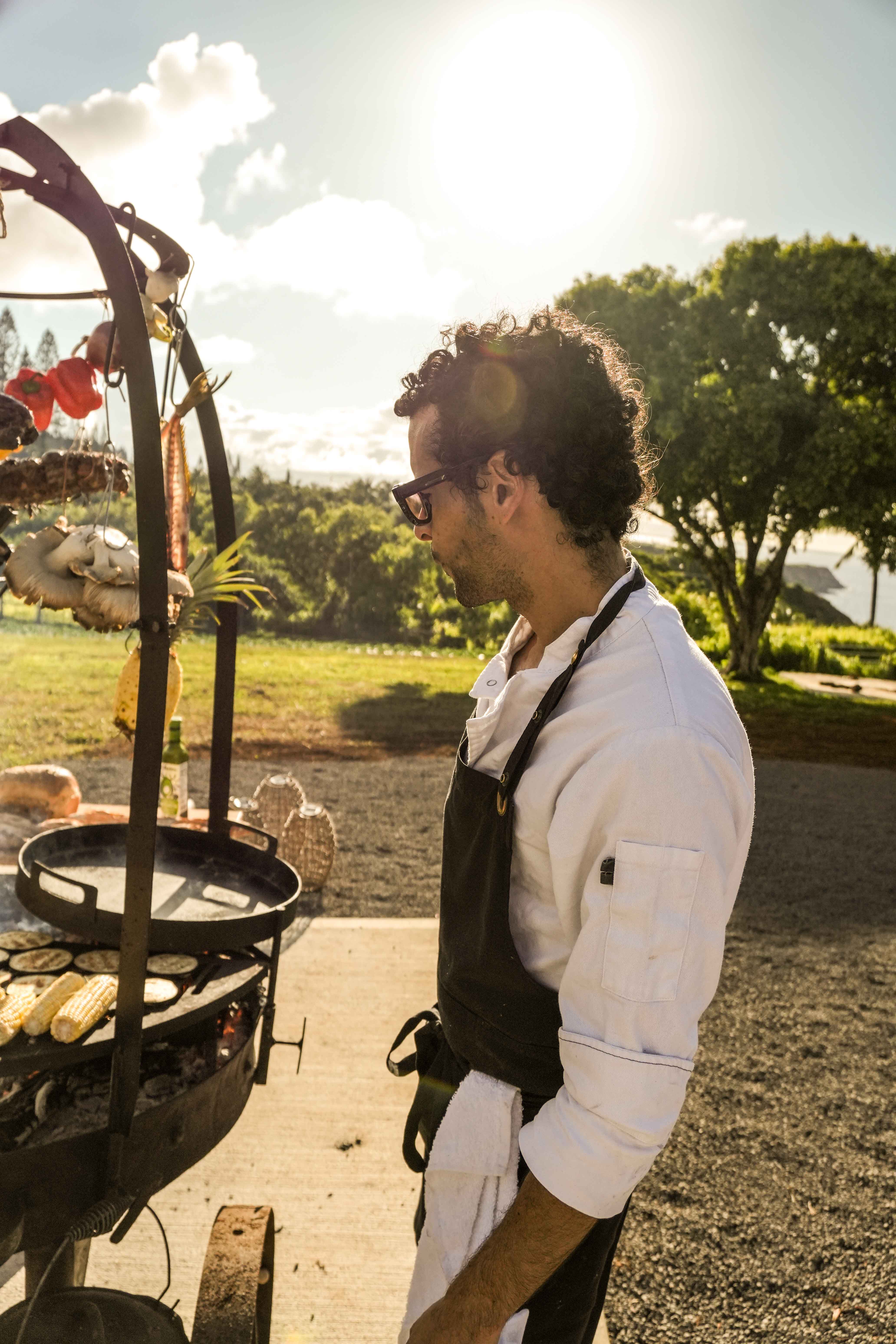 Chef Agustin tending the asado fire at golden hour