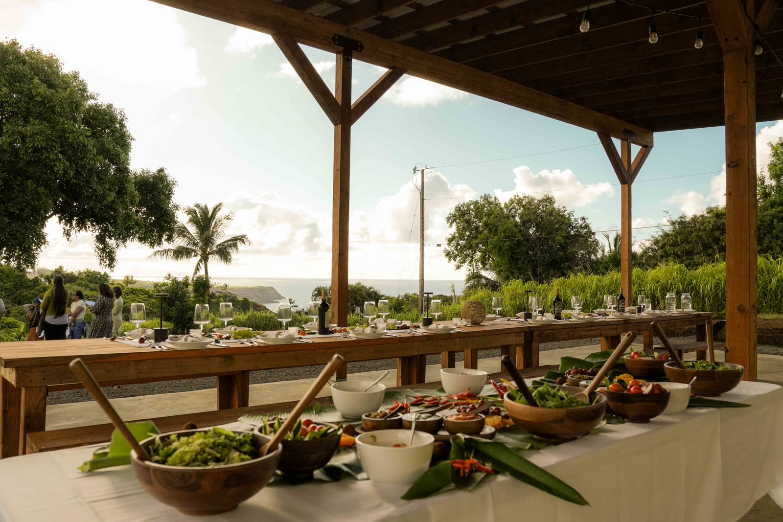 Long farm-to-table dining setup under the pavilion with ocean view